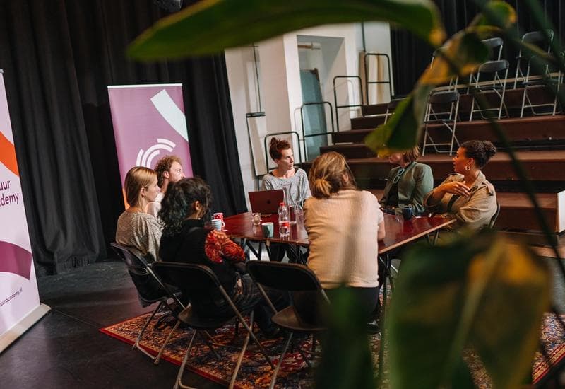 Photo of seven people at a table talking to each other during a program of Cultuur Academy